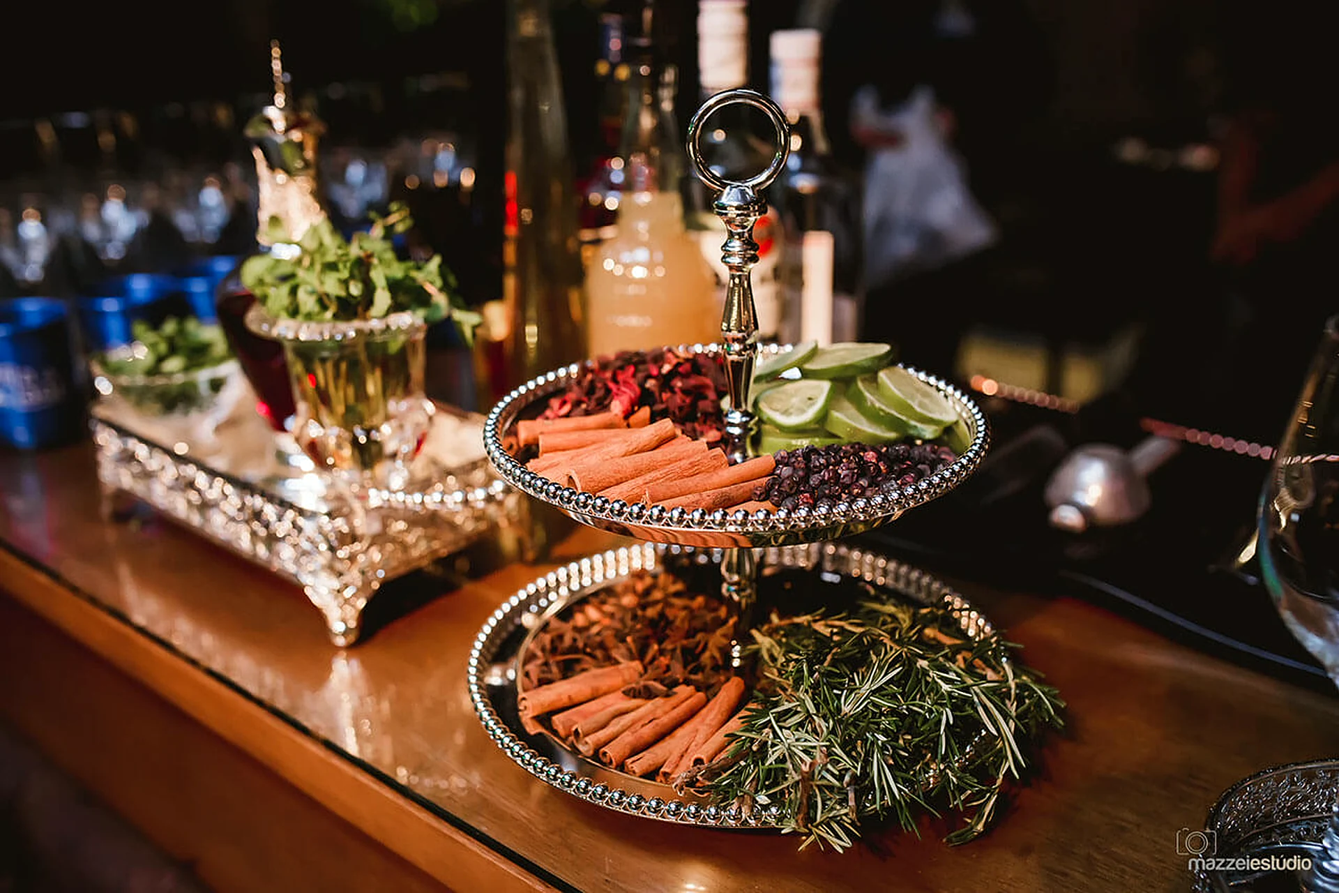 Bandeja de prata com canela, rodelas de limão, frutas secas e ervas para os drinks no balcão do bar da Villa do Lago