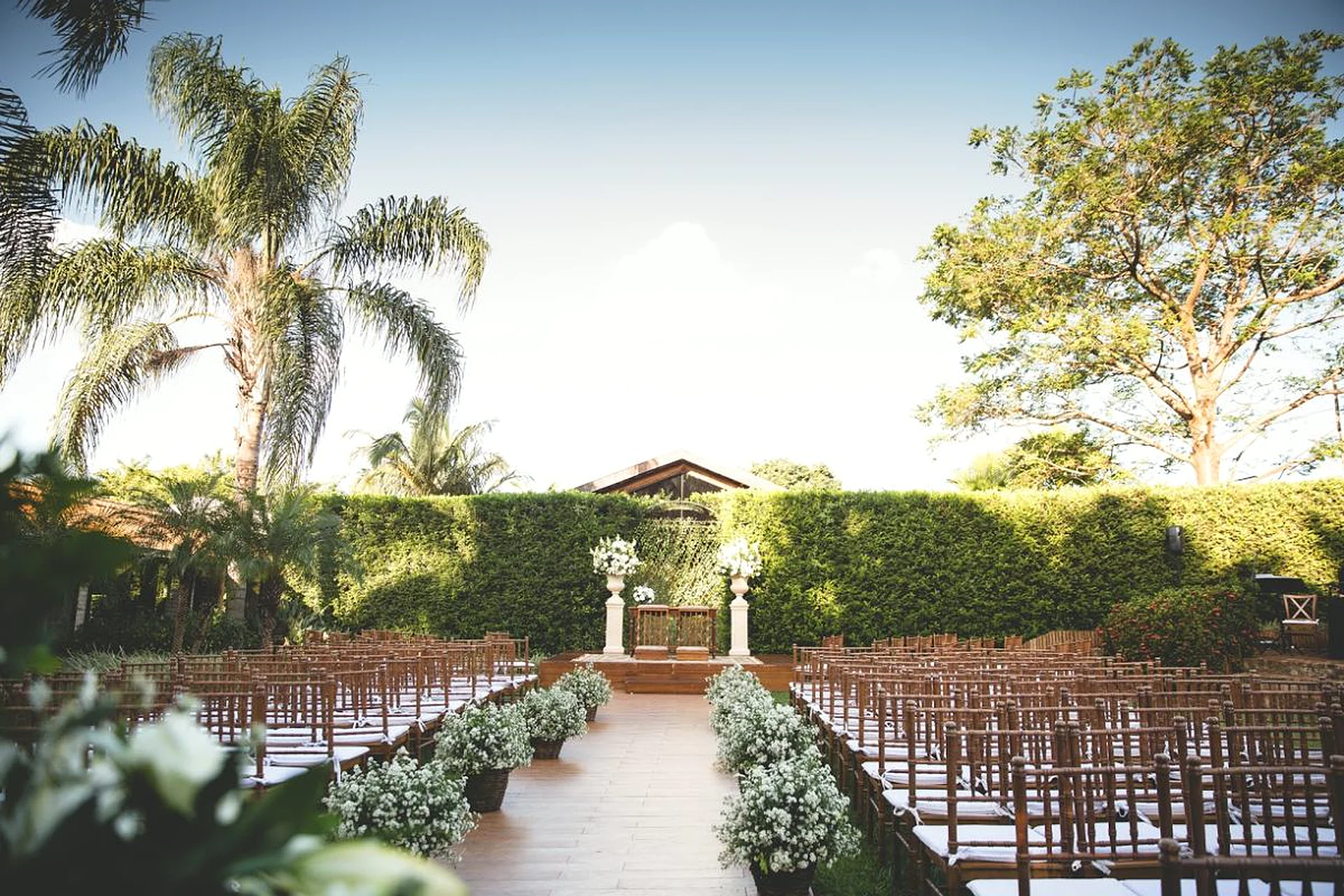 Cerimônia de casamento ao ar livre montada ao pôr do sol entre palmeiras na Villa do Lago