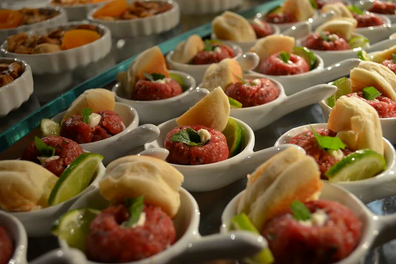 Finger food em colheres de louça enfileiradas na Villa do Lago