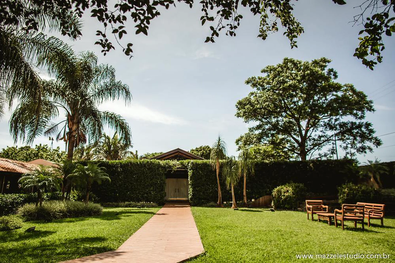 Jardim com gramado amplo, caminho e árvores na área externa da Villa do Lago