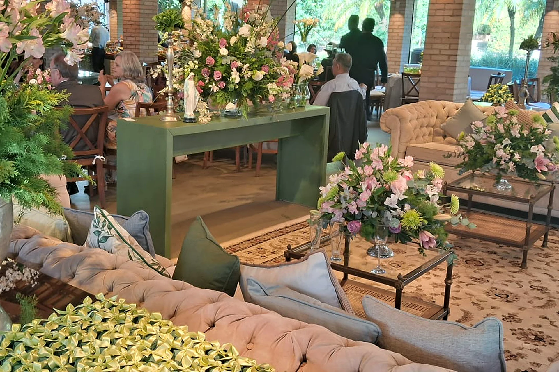 Lounge com sofás e arranjos de flores em salão da Villa do Lago