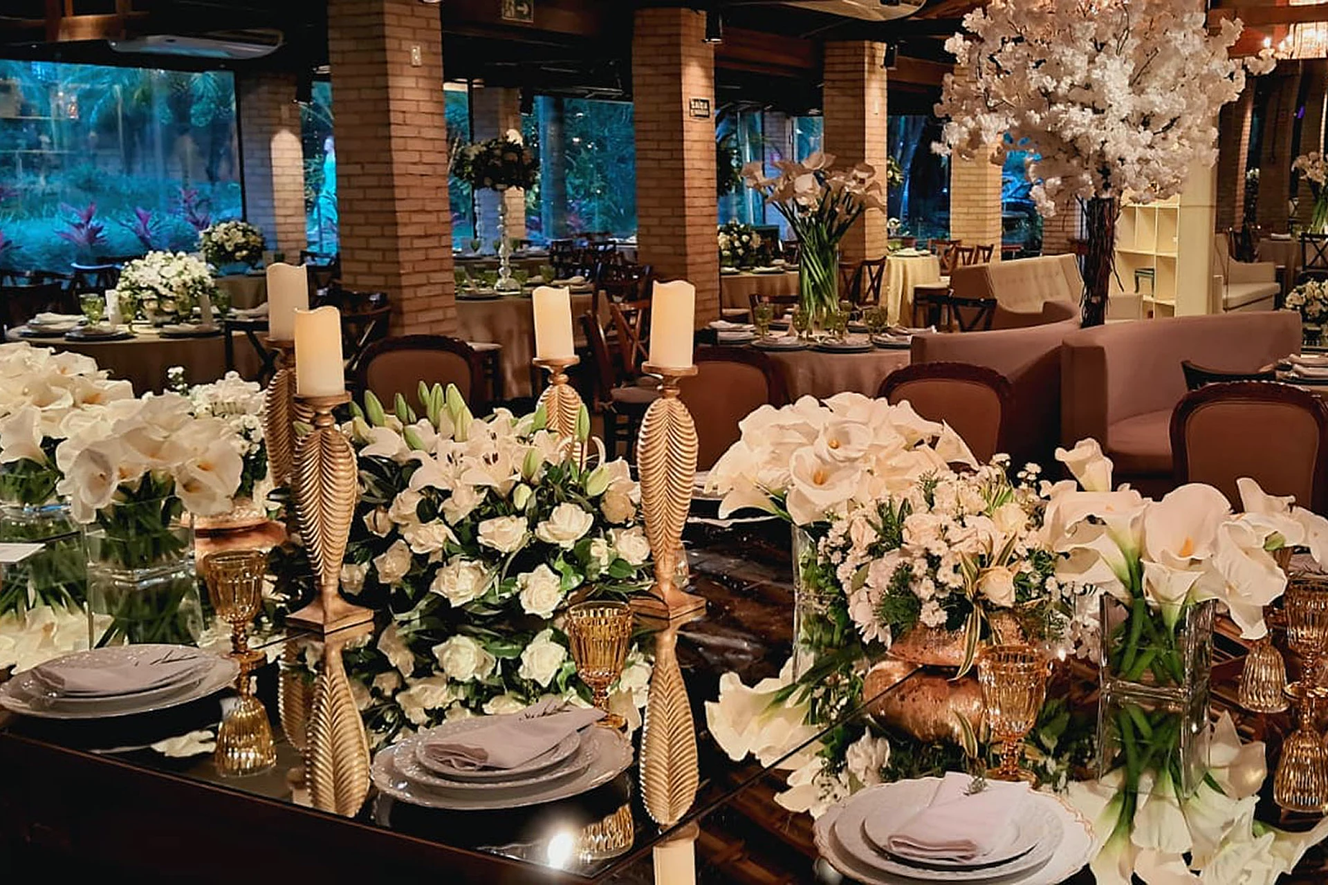 Mesa posta com flores brancas, velas e louças na Villa do Lago