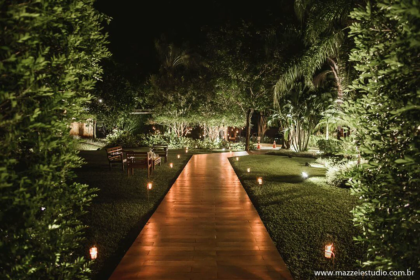 Passarela de madeira iluminada no jardim da Villa do Lago à noite