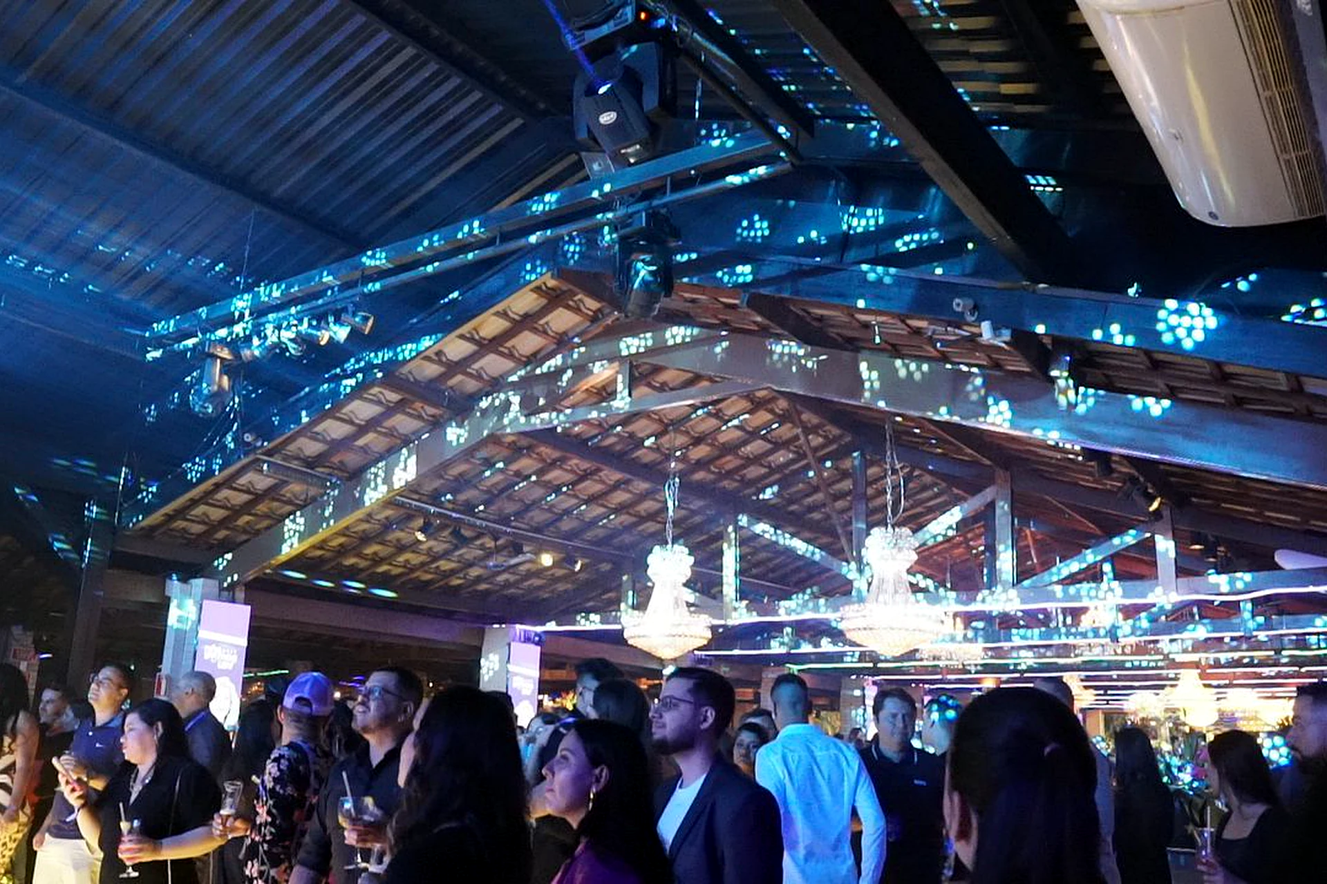 Convidados na pista de dança com iluminação azul e lustres na Villa do Lago